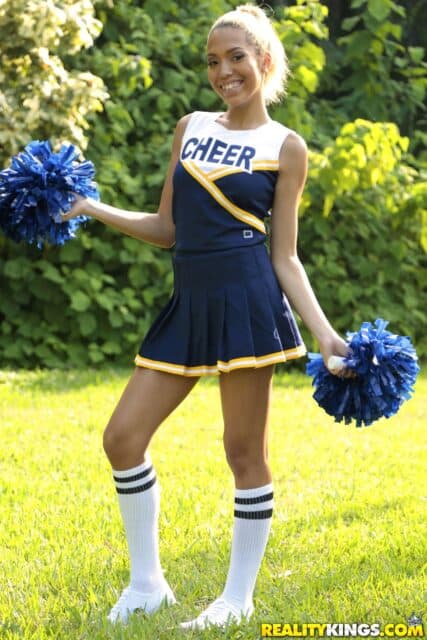 Carmella Santos XXXBios - Hot petite all natural Latina pornstar Carmella Santos aka Selena Sosa in sexy yellow, white and blue cheerleader outfit with white ankle socks, blue pom poms and white sneakers - Give Me An Oh Reality Kings Carmella Santos porn pics sfw